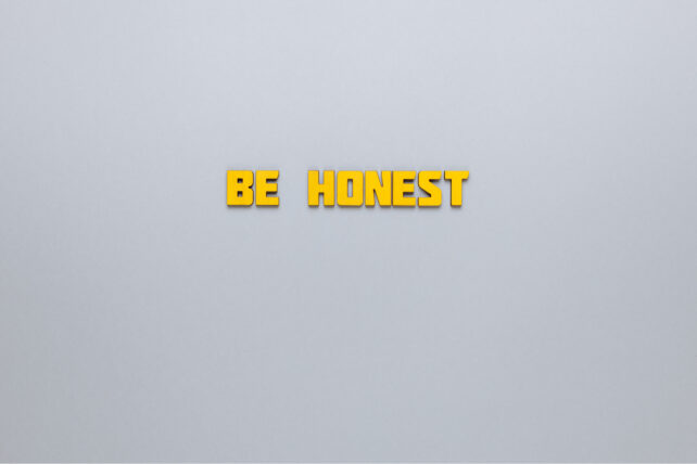 グレーの背景に黄色の文字で「BE HONEST」