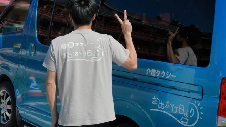 お出かけ日よりの車両とTシャツを強調した白井さんの写真